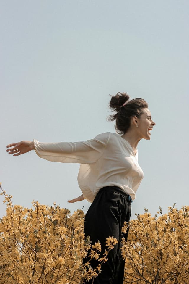 Woman with arms outstretched in a field of yellow flowers